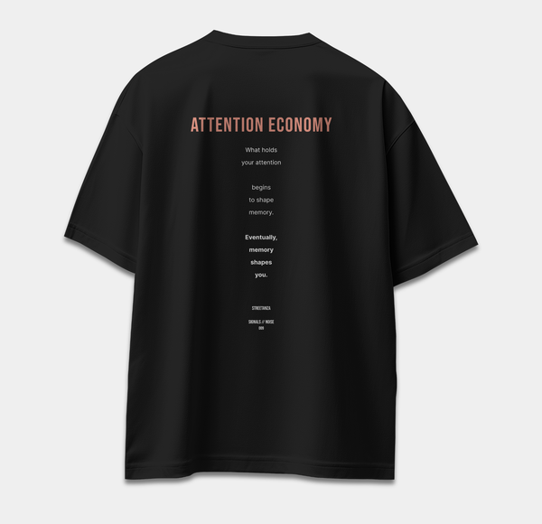 Back of black oversized T-shirt featuring ATTENTION ECONOMY text about attention and memory